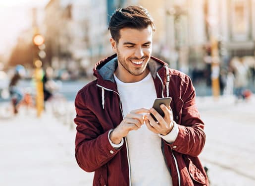 homme souriant devant son téléphone portable Europ Assistance