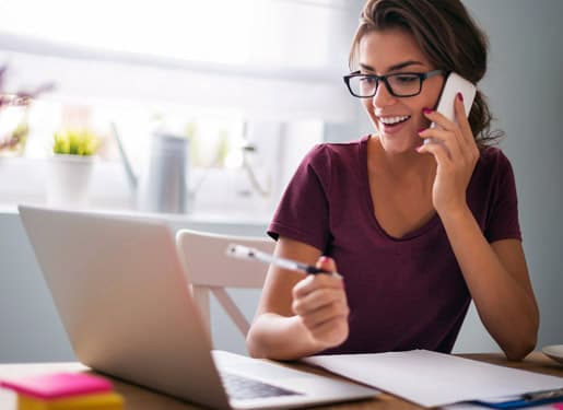 femme souriante au téléphone devant son ordinateur Europ Assistance